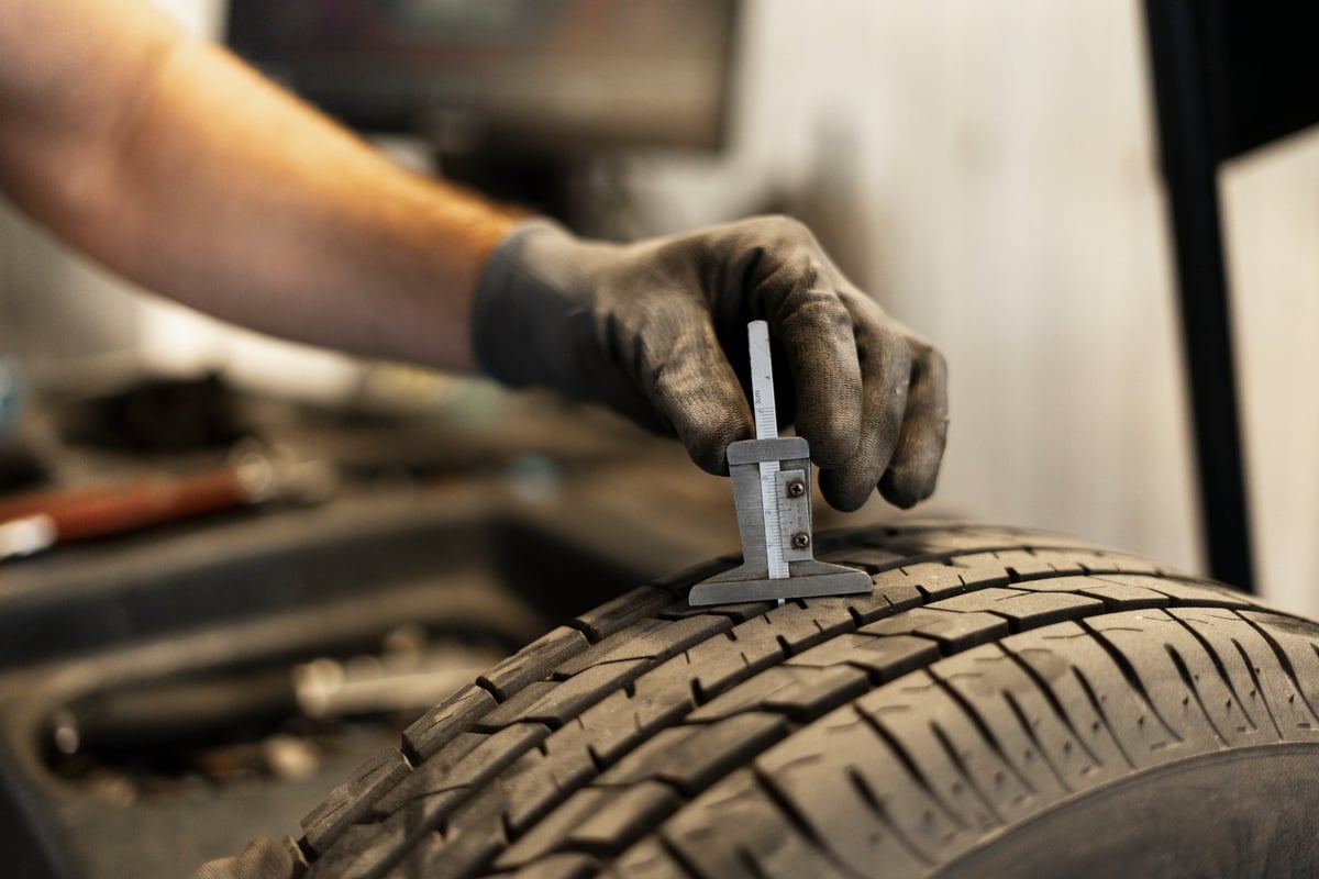 Mechanic using a caliper to check tire tread depth