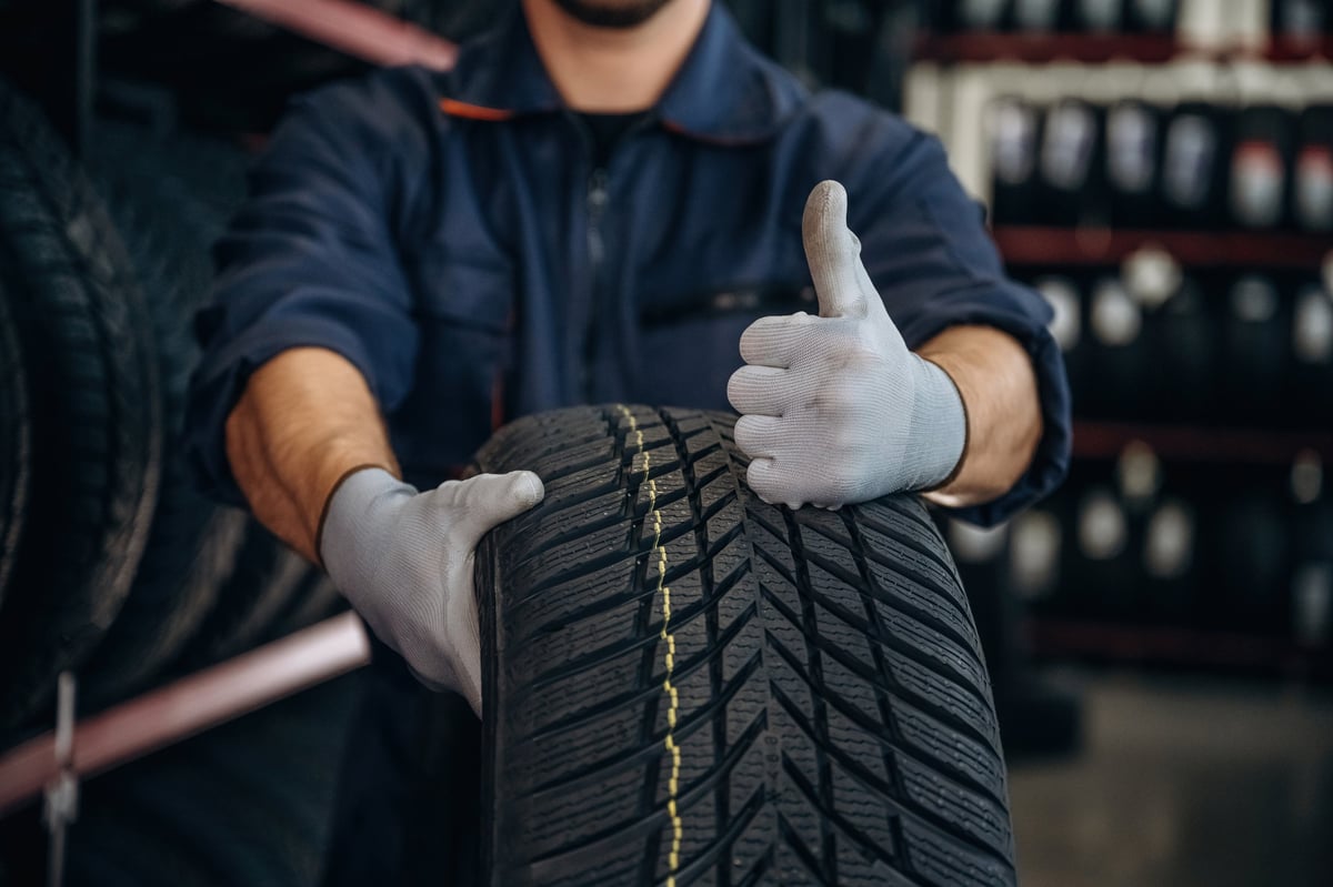 Technician giving a thumbs up while holding a tire at the maintenance station