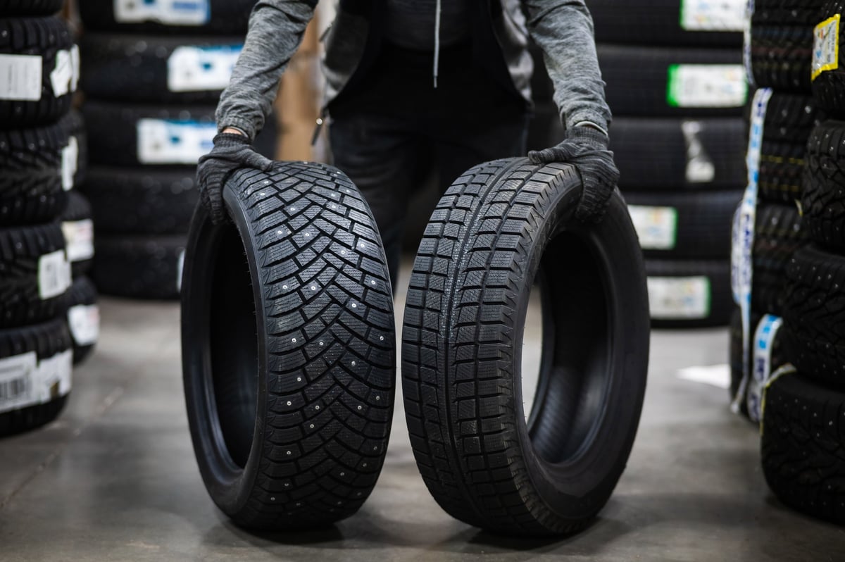 Mechanic comparing new summer and winter car tires in the garage